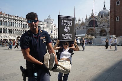 La policía se lleva a un activista con un cartel que dice "El planeta arde" durante una protesta en la plaza de San Marcos contra la boda del fundador de Amazon, Jeff Bezos, en Venecia, el 26 de junio de 2025.
