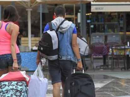 Unos turistas caminan con sus maletas por el barrio de La Barceloneta. 