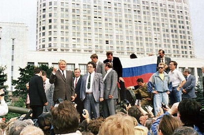 O presidente russo, Boris Yeltsin, de pé em cima de um veículo militar diante do edifício da Federação Russa, em uma imagem de 19 de agosto de 1991. Atrás dele, várias pessoas seguram uma bandeira da Federação Russa. Yeltsin se dirige à multidão para convocar uma greve geral após o golpe de Estado contra o líder soviético Mikhail Gorbachev.