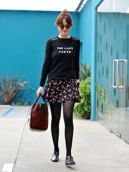 Dakota Johnson paseaba por Los Angeles con este estilismo tan inspirador para el día a día: sudadera con mensaje, falda estampada, medias y zapatos planos.