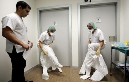 Dos sanitarias se colocan los trajes de protección contra el ébola durante los cursos de simulación en La Fe de Valencia.