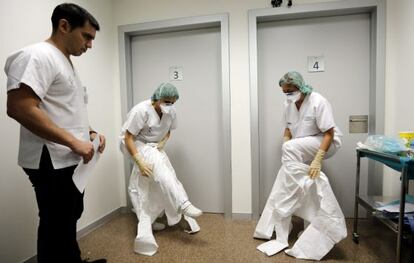 Dos sanitarias se colocan los trajes de protecci&oacute;n contra el &eacute;bola durante los cursos de simulaci&oacute;n en La Fe de Valencia.