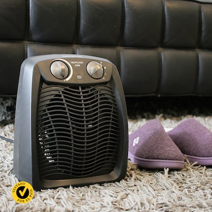 Un calefactor portátil con unas zapatillas en el salón de una casa.