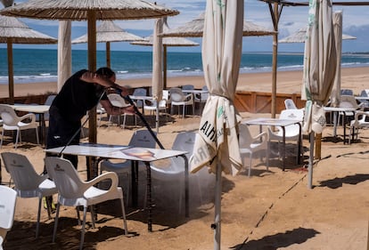 Un trabajador de un chiringuito de Punta Umbría (Huelva), durante la desinfección este domingo de la terraza del local.