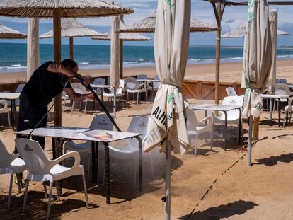 Un trabajador de un chiringuito de Punta Umbría (Huelva), durante la desinfección este domingo de la terraza del local.