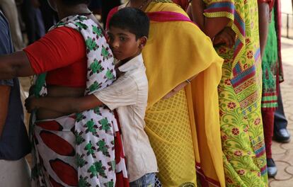 Un niño se aferra a la cintura de su madre mientras esperan para votar en un colegio electoral en Bombay (India).