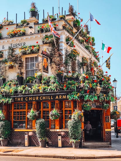 El Churchill Arms Pub decorado con muchas macetas de flores y banderas Kensington, Londres. 