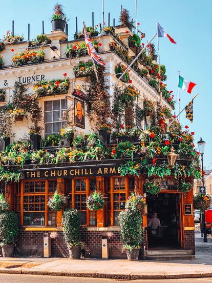 El Churchill Arms Pub decorado con muchas macetas de flores y banderas Kensington, Londres.