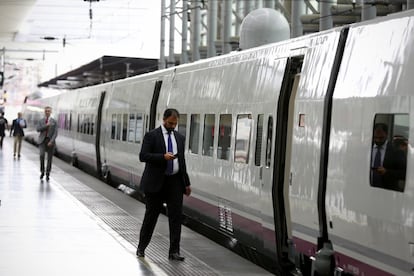 Un passatger mira el mòbil abans d'entrar en un tren AVE.