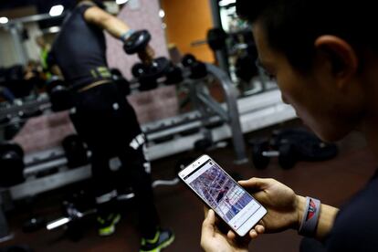 Fitness trainer Bi Zhenbo looks at a video of a high bar routine by Shi Shenwei at a gym in Beijing, China, October 5, 2016. “I think this person gives a lot of inspiration to us. And I think he’s really amazing. He inspires more and more young people to do what they like, like working out. I think he’s doing something very meaningful,” Bi said about Shi Shenwei.  REUTERS/Thomas Peter       SEARCH "BRICK CARRIER" FOR THIS STORY. SEARCH "WIDER IMAGE" FOR ALL STORIES.  