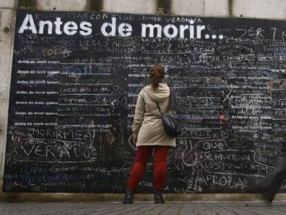 Una mujer escribe su deseo en el muro 'Antes de morir quiero...'.