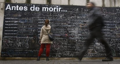 Una mujer escribe su deseo en el muro 'Antes de morir quiero...'.