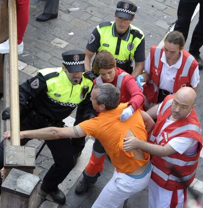 Cinco corredores han sido trasladados al Complejo Hospitalario de Navarra por diversos traumatismos tras el tercer encierro de los Sanfermines y, según las primeras informaciones de los servicios sanitarios, no se han registrado heridos por asta. En la imagen, un mozo es atendido por personal sanitario tras ser embestido por uno de los toros.