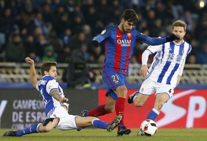 El centrocampista portugués del F. C. Barcelona, André Gomes (c), intenta llevarse el balón ante los jugadores de la Real Sociedad, Íñigo Matinez (i) y Asier Illarramendi.