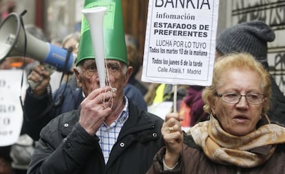 Dos ancianos con carteles proestan frente a la Audiencia Nacional.