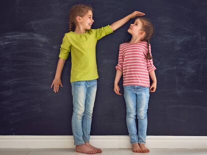 Dos niñas comparan su altura.