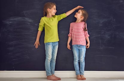 Dos niñas comparan su altura.