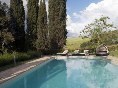 La piscina está situada en la parte trasera de la finca,
junto a su frondoso jardín. Las tumbonas son de ratán,
y la cama redonda con capota, de Kettal.