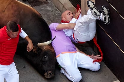 Dos mozos caen al duelo con uno de los toros este lunes, durante el cuarto encierro.