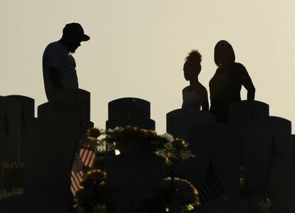 Varias personas visitan una tumba en el Cementerio Nacional de Leavenworth en la víspera del Día de los caídos en guerra, este domingo.