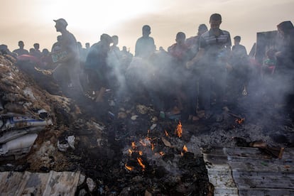 Varias personas inspeccionan los restos de un incendio provocado por un bombardeo de Israel sobre Rafah, en Gaza.