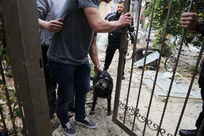 Un policía israelí desajola a un perro de una casa contigua a la vivienda impactada por el cohete.