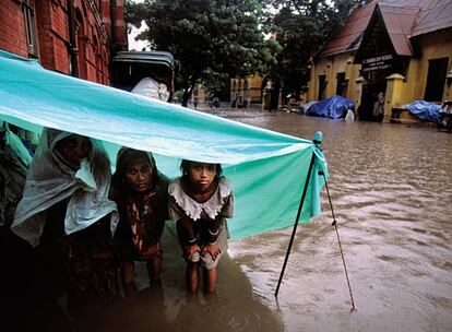 Hija, madre y abuela se refugian del monzón en una calle de Calcuta. Espera que el agua que lo anega todo salga de la precaria vivienda en la que viven y puedan volver a la vida cotidiana, de jornadas duras de trabajo, discriminación y falta de oportunidades. La mayoría de las 1.500 millones de personas que viven con menos de un euro al día son mujeres.