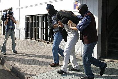 Un policía encapuchado escolta a uno de los detenidos a su salida de la Comisaría de Arrecife.