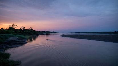 Personas viajan en una pequeña embarcación por el río.