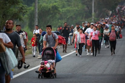 Un hombre empuja un carrito con dos infantes mientras camina por la carretera en Álvaro Obregón (Chiapas), en camino a la Ciudad de México, este lunes.