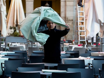 Un trabajador de la hostelería prepara una mesa en una terraza.