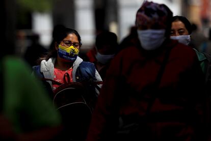 Várias pessoas com máscaras caminham por uma rua de Quito, em 25 de agosto.