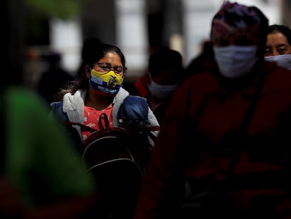 Várias pessoas com máscaras caminham por uma rua de Quito, em 25 de agosto.