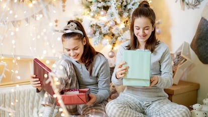 Dos adolescentes abriendo regalos el día de Navidad.