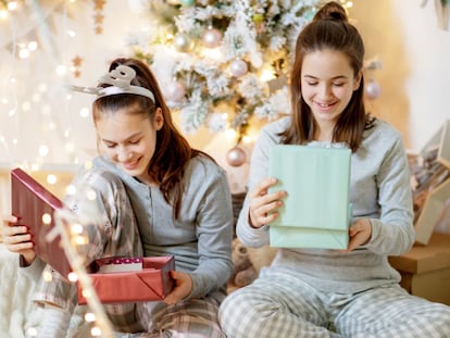 Dos adolescentes abriendo regalos el día de Navidad.
