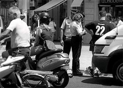 Guardias urbanos poniendo multas en una calle de Barcelona.