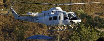 Un helicóptero carga agua de una piscina para apagar el incendio de Málaga.