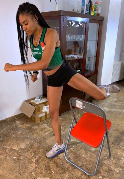 La futbolista y atleta Salma Paralluelo, entrenando con una silla en su casa la técnica del salto de vallas.