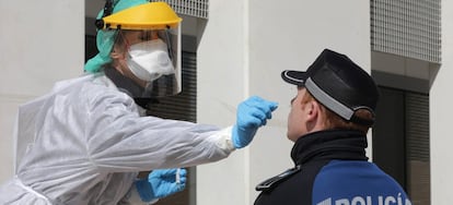 A Madrid public health worker handles a swab to test a police officer in March.