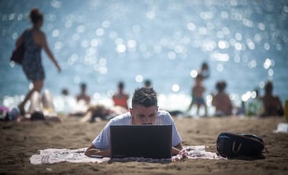 Un hombre usa un ordenador en la playa.