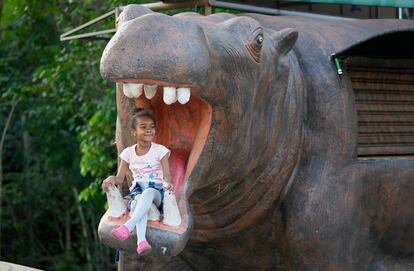 Una niña posa para una foto en la boca de una estatua de hipopótamo en el Parque Nápoles.