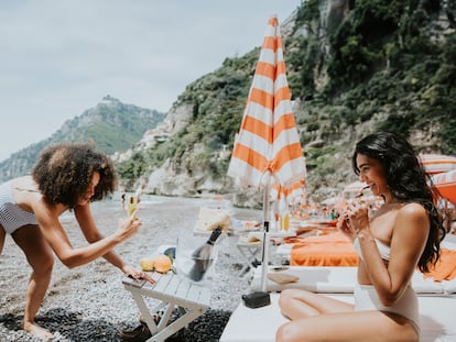 A woman takes an Instagram photo on a beach.