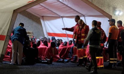 Miembros de la Cruz Roja y de la Guardia Civil atienden este jueves a un grupo de inmigrantes que ha llegado a Arguineguín (Gran Canaria).