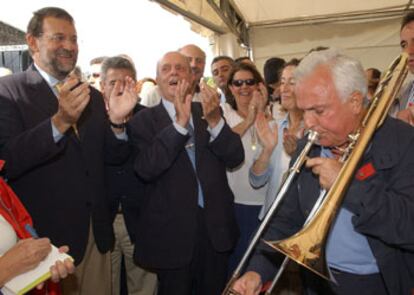 Mariano Rajoy y Manuel Fraga escuchan al presidente del PP de Ourense, José Luis Baltar, tocar el trombón.