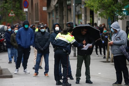 Una agente informa a personas hacen cola en el Centro de Servicios Sociales del barrio del Raval de Barcelona.