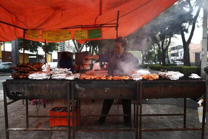 Una mujer utiliza viejos barriles a modo de barbacoa para cocinar pollo en México D.F. La imagen se tomó en la capital del país el 15 de febrero.