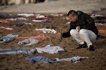 Un hombre hace una foto a las prendas colocadas en la arena.