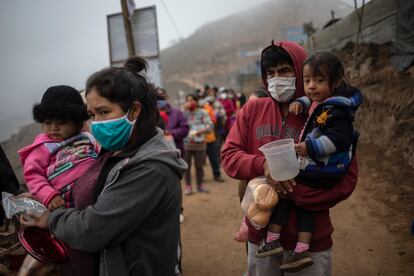 Familias hacen cola para recibir un almuerzo gratuito de una olla comunitaria, en el barrio de Nueva Esperanza de Lima, Perú, junio de 2020. 