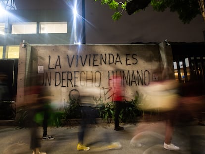 Ciudadanos pasan frente a una pinta que dice: "La vivienda es un derecho humano", en Ciudad de México.