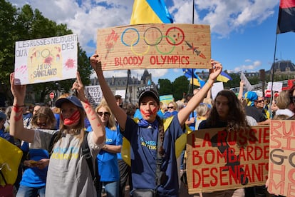 Una mujer sostiene un cartel con la leyenda "Juegos Olímpicos sangrientos" durante una marcha en memoria de los cientos de atletas ucranianos asesinados desde la invasión rusa de Ucrania el 13 de julio de 2024 en París, Francia.
